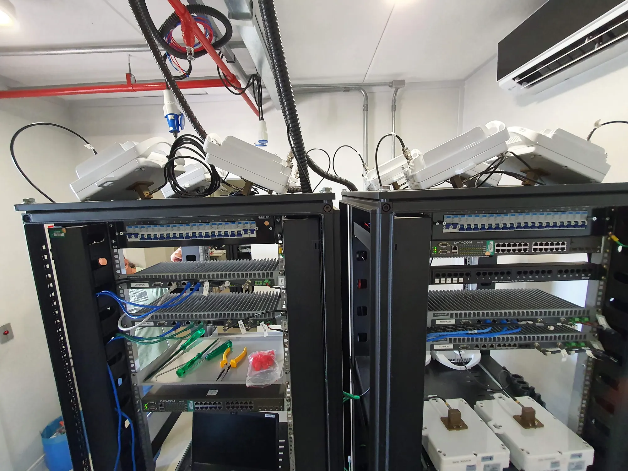 Dois racks abertos durante a integracao, com radios, switches e disjuntores instalados